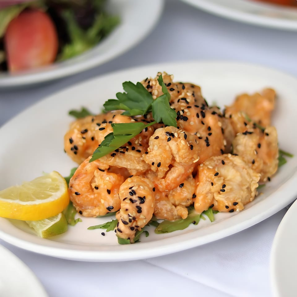 Crispy shrimp with sesame seeds and parsley, garnished with lemon and lime wedges at Mickey's Downtown Bistro.